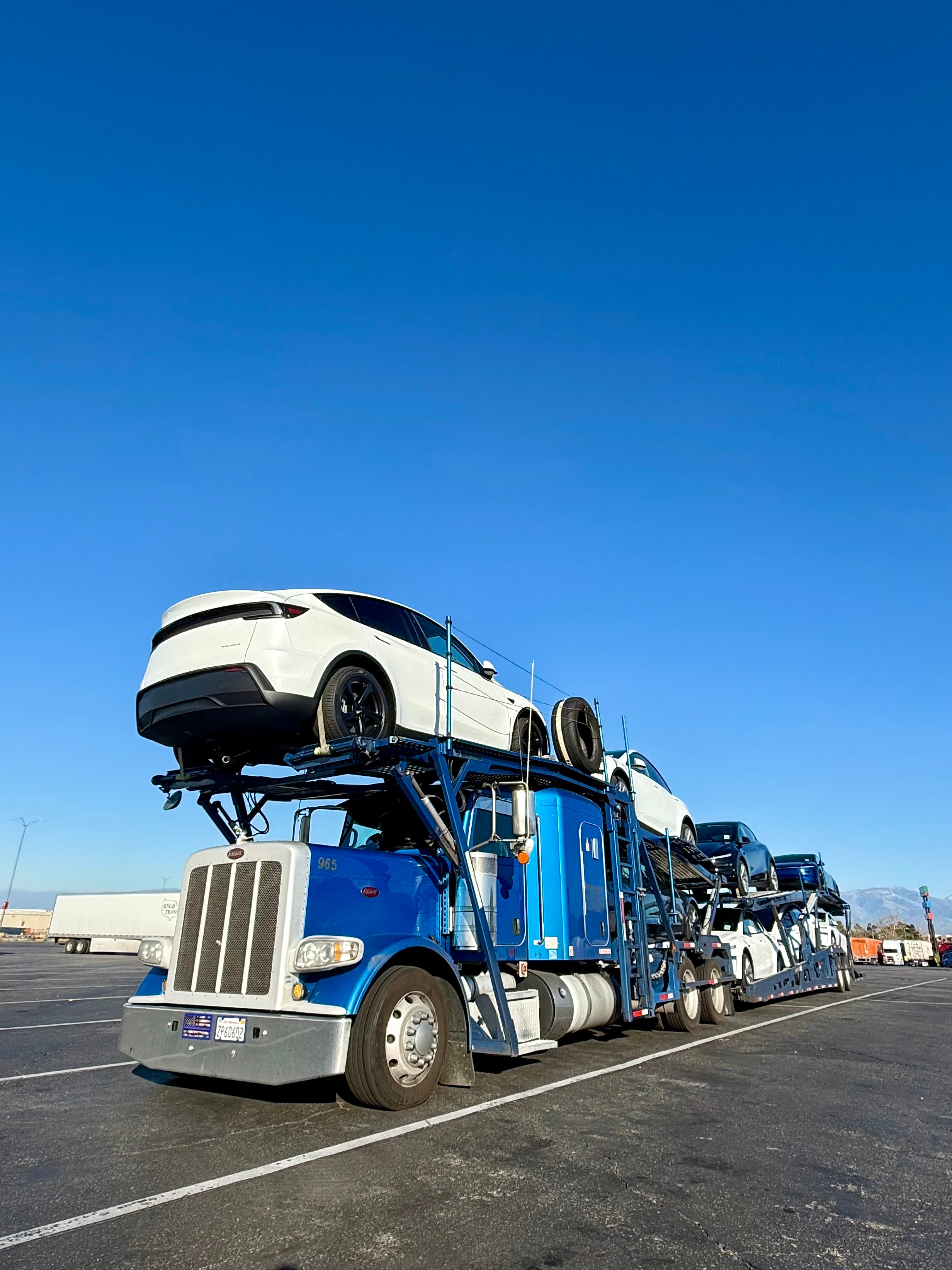 Great West Auto blue car carrier truck loaded with vehicles in a transport yard