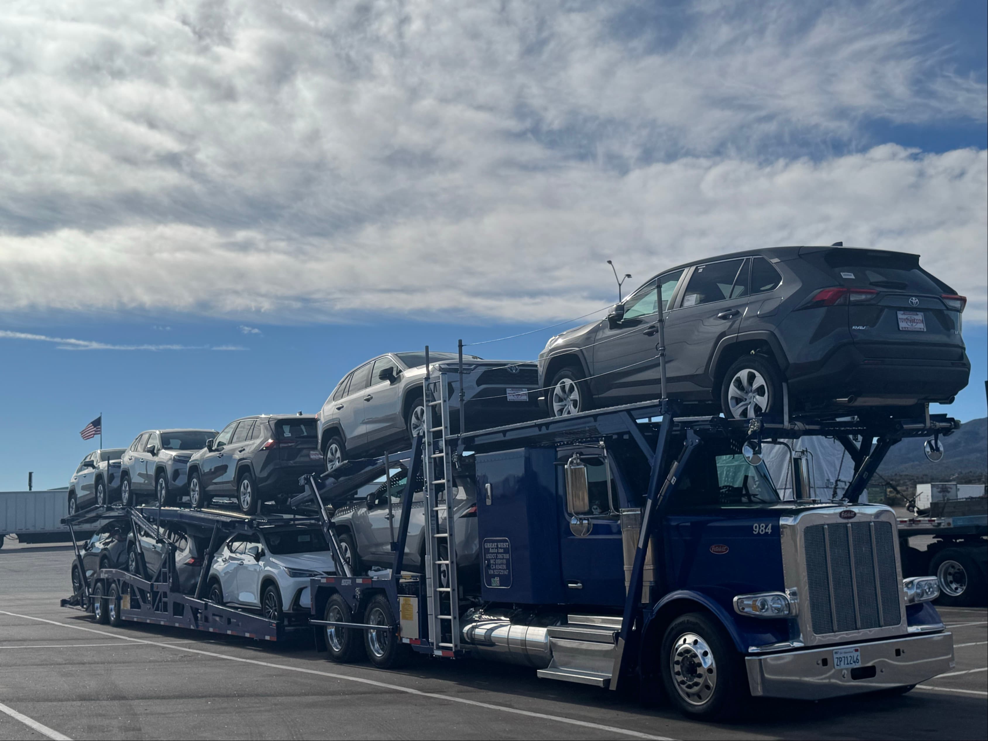 Great West Auto loaded car carrier truck parked in a transport yard